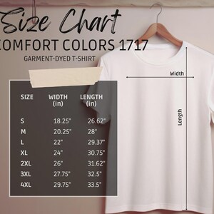 May include: A white Comfort Colors 1717 garment-dyed t-shirt hanging on a wooden hanger. The image includes a size chart with measurements in inches for sizes S through 4XL, detailing width and length.