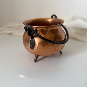 Caldero antiguo de cobre martillado, asa de hierro forjado, patas de trípode de latón, macetero de mediados de siglo.