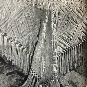 May include: A crocheted throw blanket with a fringe border. The blanket is made with a white yarn and has a delicate, intricate pattern.