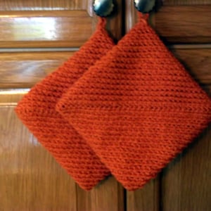May include: Two orange crocheted pot holders hanging from cabinet knobs.