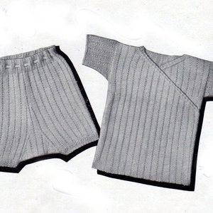 Puede incluir: Un conjunto de bebé de punto gris con una camiseta de manga corta y pantalones cortos. La camiseta tiene un escote de envoltura.