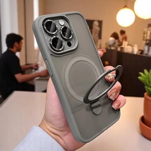 Könnte beinhalten: Eine graue Handyhülle mit einem durchsichtigen Ringhalter. Die Hülle hat eine erhöhte Kamerabuckel mit drei schwarzen Kameraobjektiven.