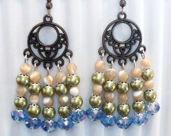 May include: A pair of dangle earrings with a bronze filigree design and multiple layers of beads. The beads are green, beige, and light blue.