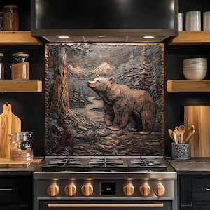 May include: A copper-toned relief sculpture of a bear in a forest scene, mounted above a stainless steel stove. The bear is brown, with a river and mountains in the background. The kitchen has dark cabinets and wooden shelves.