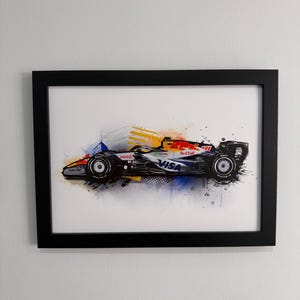 May include: Framed art print of a Formula 1 race car. The car is black, red, and white, with sponsor logos including "VISA" and "Red Bull." The artwork features colourful paint splatters and a black frame.