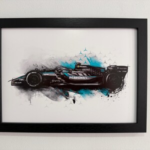 May include: Framed art print of a Formula 1 race car in black, teal, and white. The car features the "PETRONAS" logo and other sponsor details. The artwork has a dynamic, artistic style with paint splatters and geometric shapes.