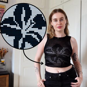 Könnte beinhalten: Schwarzes Mesh-Crop-Top mit floralem Design. Das Top ist ärmellos und hat einen runden Ausschnitt. Das florale Design wird auch in einer Nahaufnahme gezeigt. Das Model trägt eine schwarze Jeans.