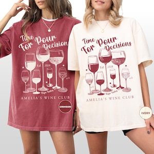 以下が含まれることがあります： ワインをテーマにしたグラフィックが特徴の2枚のTシャツ。1枚はクリムゾン、もう1枚はアイボリー。デザインにはワイングラス、「Time For Pour Decisions」の文字、「AMELIA'S WINE CLUB」が含まれています。クリムゾンシャツには「CRIMSON」のラベルが付いています。