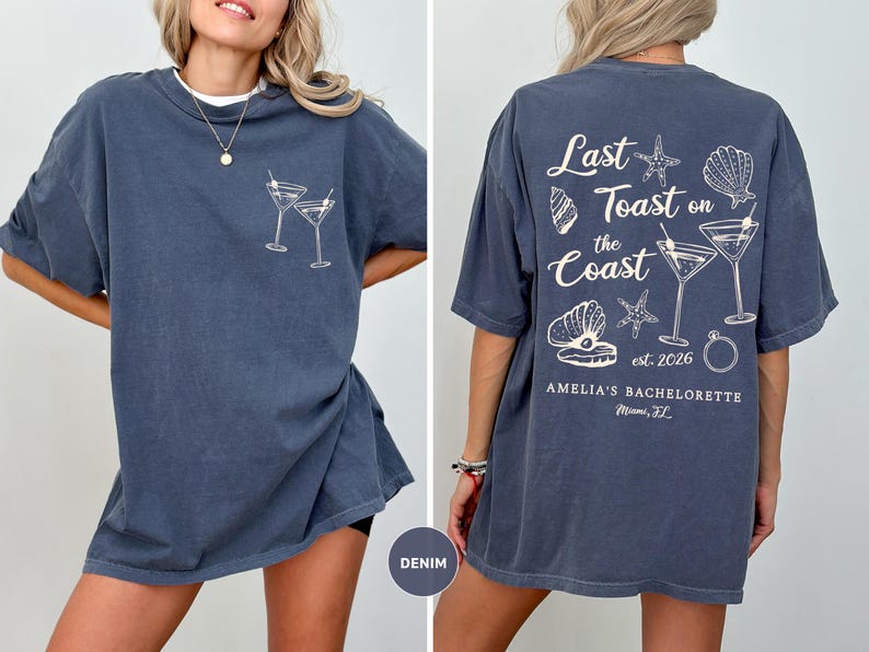 K&ouml;nnte beinhalten: Denimblaues T-Shirt mit einem Frontmotiv aus zwei Martinigl&auml;sern und einem R&uuml;ckenmotiv mit dem Text "Last Toast on the Coast", Muscheln, Seesternen und Martinigl&auml;sern. Der Text "Amelia's Bachelorette Miami, FL" ist ebenfalls auf der R&uuml;ckseite aufgedruckt.