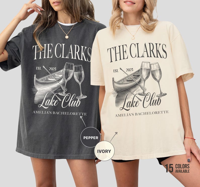 May include: Two oversized t-shirts, one pepper and one ivory, featuring a boat, wine glasses, and the text "THE CLARKS LAKE CLUB AMELIA'S BACHELORETTE EST. 2025". The shirts are casual and comfortable.