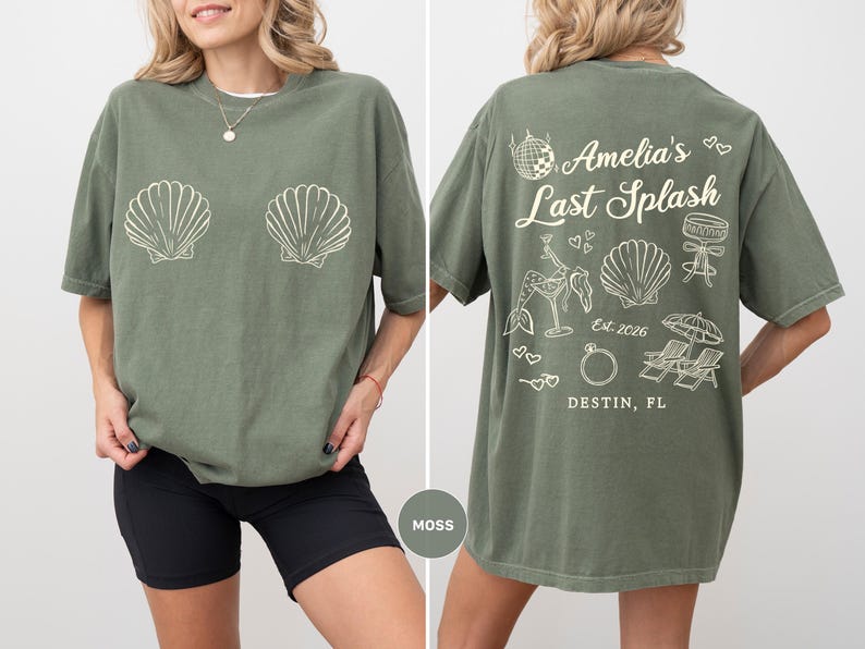 Puede incluir: Camiseta verde musgo con gr&aacute;ficos de conchas blancas en la parte delantera. La parte trasera de la camiseta presenta el texto "Amelia's Last Splash" con gr&aacute;ficos adicionales. La camiseta es de corte holgado.