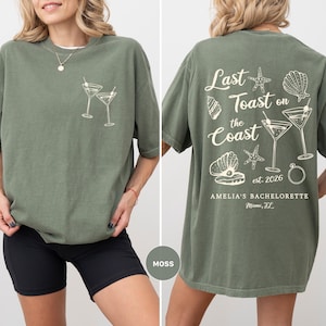 K&ouml;nnte beinhalten: Moosgr&uuml;nes T-Shirt mit einer Grafik von zwei Martinigl&auml;sern auf der Vorderseite. Auf der R&uuml;ckseite steht der Text "Last Toast on the Coast" mit Muschel- und Seestern-Illustrationen sowie der Text "est. 2026" und "AMELIA'S BACHELORETTE Miami, FL".