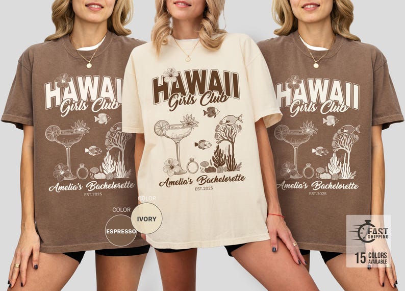 K&ouml;nnte beinhalten: Espresso- und elfenbeinfarbene T-Shirts mit dem Text "HAWAII Girls Club" im Vintage-Stil. Die Shirts zeigen ein tropisches Design mit einem Cocktail, Fischen und Korallen. Der Text "Amelia's Bachelorette EST. 2025" ist ebenfalls aufgedruckt.