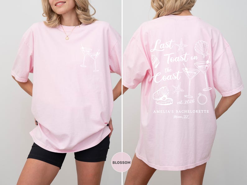 K&ouml;nnte beinhalten: Hellrosa &uuml;bergro&szlig;es T-Shirt mit wei&szlig;en Grafikdesigns. Die Vorderseite zeigt ein Cocktailglas-Design, w&auml;hrend die R&uuml;ckseite den Text "Last Toast on the Coast" mit Muschel- und Cocktail-Illustrationen zeigt. F&uuml;r Amelias Junggesellinnenabschied.