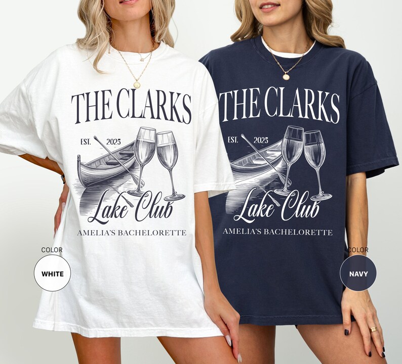 May include: White and navy blue t-shirts with a graphic design. The design includes the text "THE CLARKS Lake Club" with a boat, champagne glasses, and the text "AMELIA'S BACHELORETTE". The shirts are a relaxed fit.