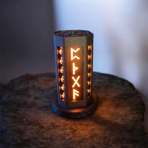 May include: A gray, hexagonal lantern with illuminated orange runes. The lantern has a decorative top and sits on a circular base. The runes are centered on the front of the lantern, and there are decorative cutouts on the sides.