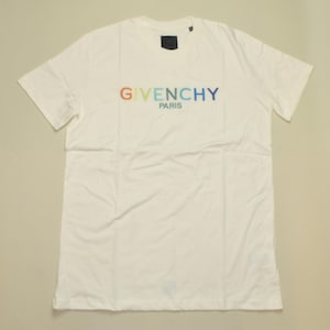 Può includere: T-shirt bianco con la scritta "GIVENCHY PARIS" stampata in un gradiente di colori sul petto. La maglietta ha maniche corte e scollo tondo. Il tessuto sembra essere cotone.