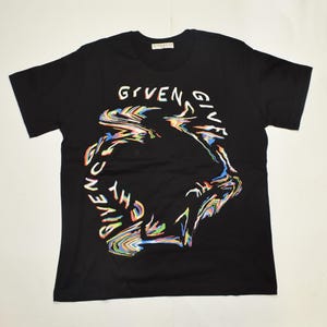 May include: Black crew neck t-shirt with a colourful, abstract "GIVENCHY" design. The design incorporates rainbow colours. The brand name is visible on the neckline. A casual, everyday garment.
