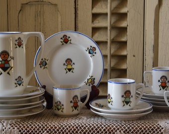 May include: A vintage children's tea set with a white background and colorful cartoon figures. The set includes a pitcher, cups, saucers, and a plate.