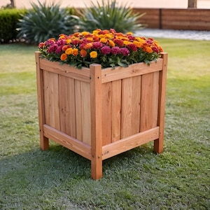 Peut inclure: Un bac à fleurs carré en bois rempli de fleurs orange, jaunes et rouges vibrantes. Le bac est en bois brun clair et repose sur de petits pieds, placé sur une pelouse verte. Les fleurs sont en pleine floraison.