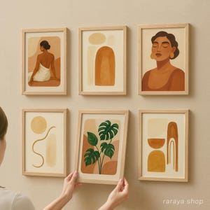 May include: Set of six minimalist art prints in wooden frames. The prints feature abstract shapes, a woman with closed eyes, and a green tropical plant. The prints are in shades of brown, beige, and green.