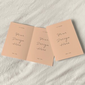May include: A folded card mockup with a peach background. The card is 5 x 7 inches and has the text "Your Design Here" written in cursive on the front. The card is folded in half and the inside is blank.