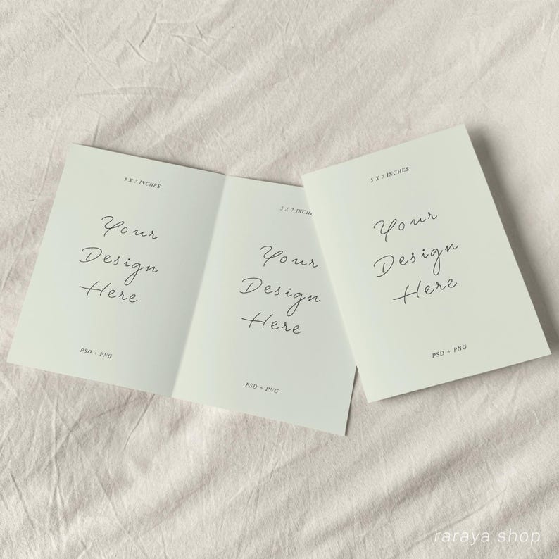May include: A folded card mockup with a light green background. The card is 5.5 x 7 inches and has the text "Your Design Here" on each side. The card is on a white fabric surface.