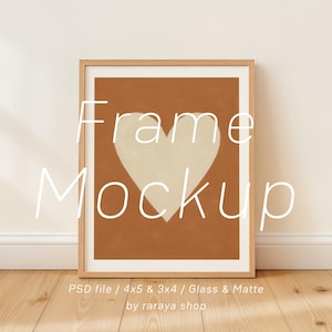 Puede incluir: Una impresión enmarcada con un gran corazón blanquecino sobre un fondo color terracota, dentro de un marco de madera clara. La imagen incluye el texto "Frame Mockup" y detalles del producto. La obra se exhibe sobre un suelo de madera.