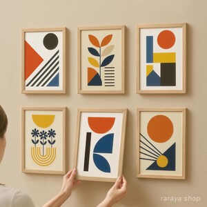 May include: Set of six framed abstract art prints with geometric shapes and patterns in shades of orange, yellow, blue, and black. The prints are in wooden frames with a light brown finish.