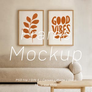 Op de afbeelding: Twee ingelijste kunstprints met een minimalistisch ontwerp. Eén heeft een roestkleurige bladerillustratie en de andere zegt "GOOD VIBES" in een bijpassende roestkleur. De frames zijn van licht hout en de prints worden boven een beige bank weergegeven.