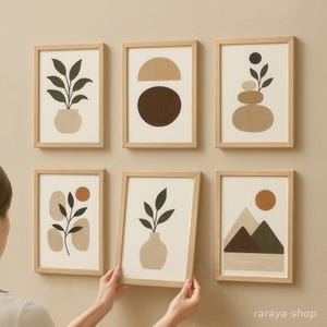 May include: Set of six minimalist art prints in wooden frames with abstract shapes and plants in neutral colors. The prints feature a plant in a pot, a brown circle, stacked stones, a plant in a vase, a mountain range, and a plant with a red circle.