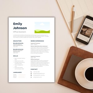 Pode incluir: Um currículo para Emily Johnson, Assistente de escritório, com seções de educação, experiência de trabalho, habilidades e idiomas. Um smartphone, caneta e xícara de café também são visíveis.
