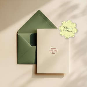 Op de afbeelding: Een crèmekleurige kaart met de rode woorden "happy you + me day", naast een open groene envelop. Een lichtgele sticker met de woorden "Digital Download" staat in de rechterbovenhoek. De kaart en envelop liggen op een beige oppervlak.