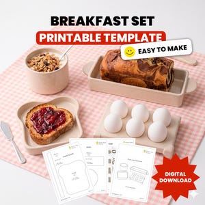 Puede incluir: Una plantilla imprimible de set de desayuno con un icono de descarga digital, un tazón de granola, un pastel de mármol en un plato rectangular, una rebanada de pan tostado con mermelada y seis huevos blancos en un soporte de cerámica.