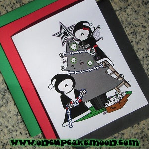 May include: A black and white illustration of two skeletons decorating a Christmas tree with skulls and bones. The tree is gray and the skeletons are wearing black clothing. The text "www.oncupcakemoon.com" is at the bottom of the image.
