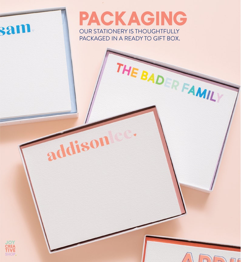 May include: A set of four personalized stationery note cards in white boxes with colorful text. The text on the cards reads "sam", "THE BADER FAMILY", "addisonlee.", and "APRIL". The boxes are on a pink background. The text "PACKAGING OUR STATIONERY IS THOUGHTFULLY PACKAGED IN A READY TO GIFT BOX." is at the top of the image.