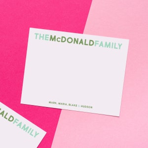 May include: White card with green text that reads "THE MCDONALD FAMILY" and "MARK, MARIA, BLAKE & HUDSON" on a pink and light pink background.