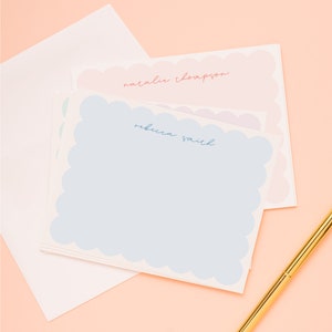 May include: Stack of blue, pink, and white stationery with scalloped edges. The top sheet has the name "natalie thompson" written in pink. The second sheet has the name "rebecca smith" written in blue.