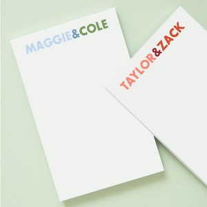 Puede incluir: Dos juegos de bloc de notas blancos con texto de colores. El bloc de notas superior dice "MAGGIE & COLE" en azul, verde y azul claro. El bloc de notas inferior dice "TAYLOR & ZACK" en rojo, naranja y rosa.