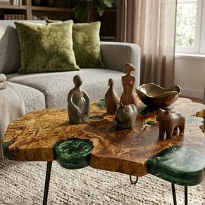 May include: A live-edge coffee table with a distinctive wood grain and green resin detailing. The table is decorated with sculptures, a brass bowl, and a wooden bear figurine. The table is supported by black metal legs. The table's dimensions are approximately 120 cm in length.