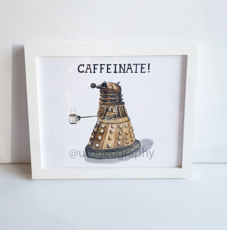 May include: A watercolor illustration of a Dalek, a fictional robot from the British science fiction television series Doctor Who, holding a cup of coffee. The Dalek is gold and has a black eye. The text "CAFFEINE!" is above the Dalek. The illustration is framed in a white frame.