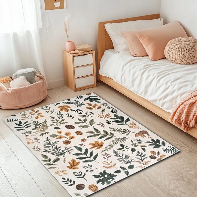 May include: A white area rug with a pattern of green and brown leaves and pine cones. The rug is on a wooden floor in a bedroom with a bed and bedside table.