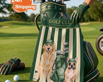 May include: A green and white striped waffle-textured golf towel featuring a golden retriever and a French bulldog, both wearing green golf caps, standing next to a golf bag. The towel has the text GOLF CLUB printed at the top.