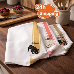 May include: Three white kitchen towels featuring vertical stripes in yellow, coral, and tan. Each towel displays a custom dog illustration and a name: a black French Bulldog labelled Miea, a cream Labrador labelled Max, and a German Shepherd labelled Cooper.