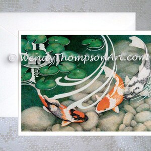 May include: Two koi fish swim in a pond with lily pads and rocks. The koi are orange, white, and black. The water is clear and blue. The pond is surrounded by green lily pads.