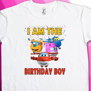 May include: White t-shirt with a colorful graphic of cartoon airplanes and the text "I AM THE BIRTHDAY BOY".