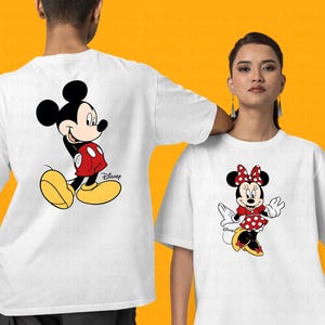 K&ouml;nnte beinhalten: Zwei wei&szlig;e T-Shirts mit einem Cartoon-Bild von Mickey Mouse und Minnie Mouse. Das Mickey Mouse Shirt zeigt Mickey Mouse in einem roten und gelben Outfit. Das Minnie Mouse Shirt zeigt Minnie Mouse in einem roten und wei&szlig;en Polka-Dot-Kleid mit einer roten Schleife.