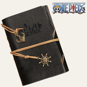 Peut inclure: Un carnet noir aspect cuir avec le logo One Piece et des silhouettes de personnages gaufrés sur la couverture. Le carnet est entouré de cordons en cuir beige, chacun orné d'une breloque ancre en bronze et d'une breloque gouvernail en métal.