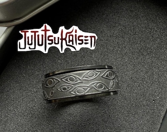 May include: A dark gray ring with an engraved eye pattern. The ring is set against a dark background, with the text "Jujutsu Kaisen" visible in the background.