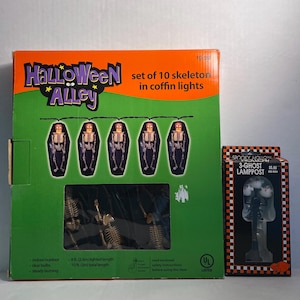 May include: A Halloween-themed box set featuring a string of 10 skeleton coffin lights. The box is green and orange with the text "Halloween Alley". A smaller box with a 3-ghost lamppost is also visible.